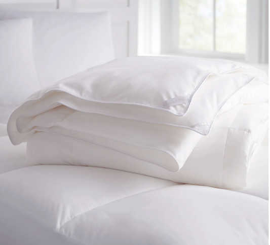 White comforter and pillow on a bed with a bright background