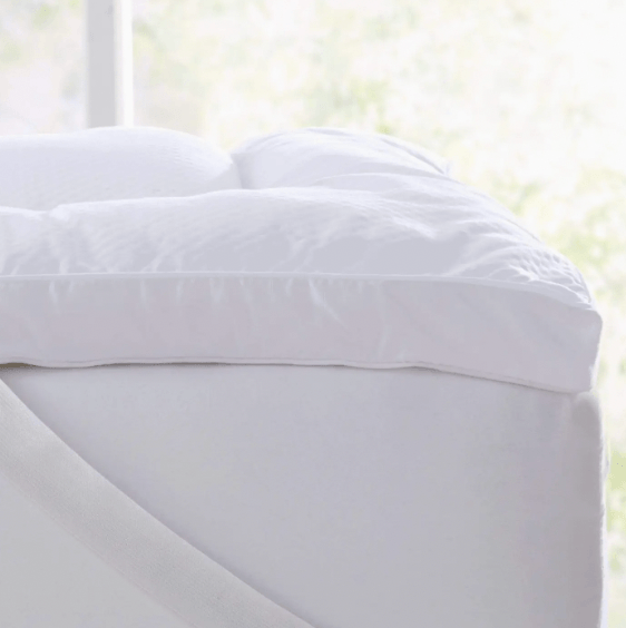 White fitted sheet on a bed with a blurred window background. The Kyle Dorm Bedding Bundle