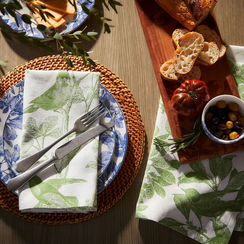 Botanical table setting with blue floral plates, woven placemats, and linen napkins