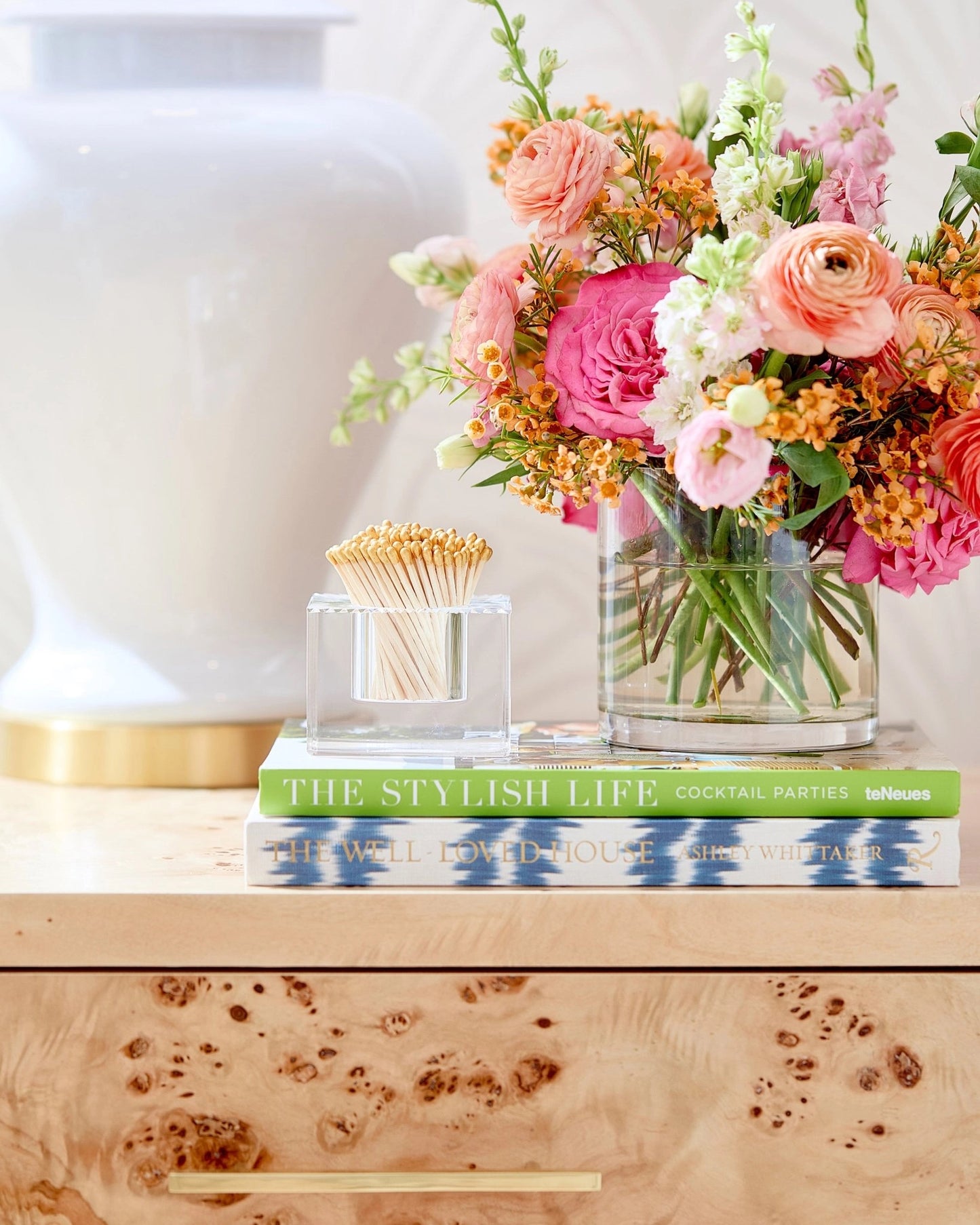 Decorative setup with books, a vase of flowers, and matchsticks on a wooden surface.