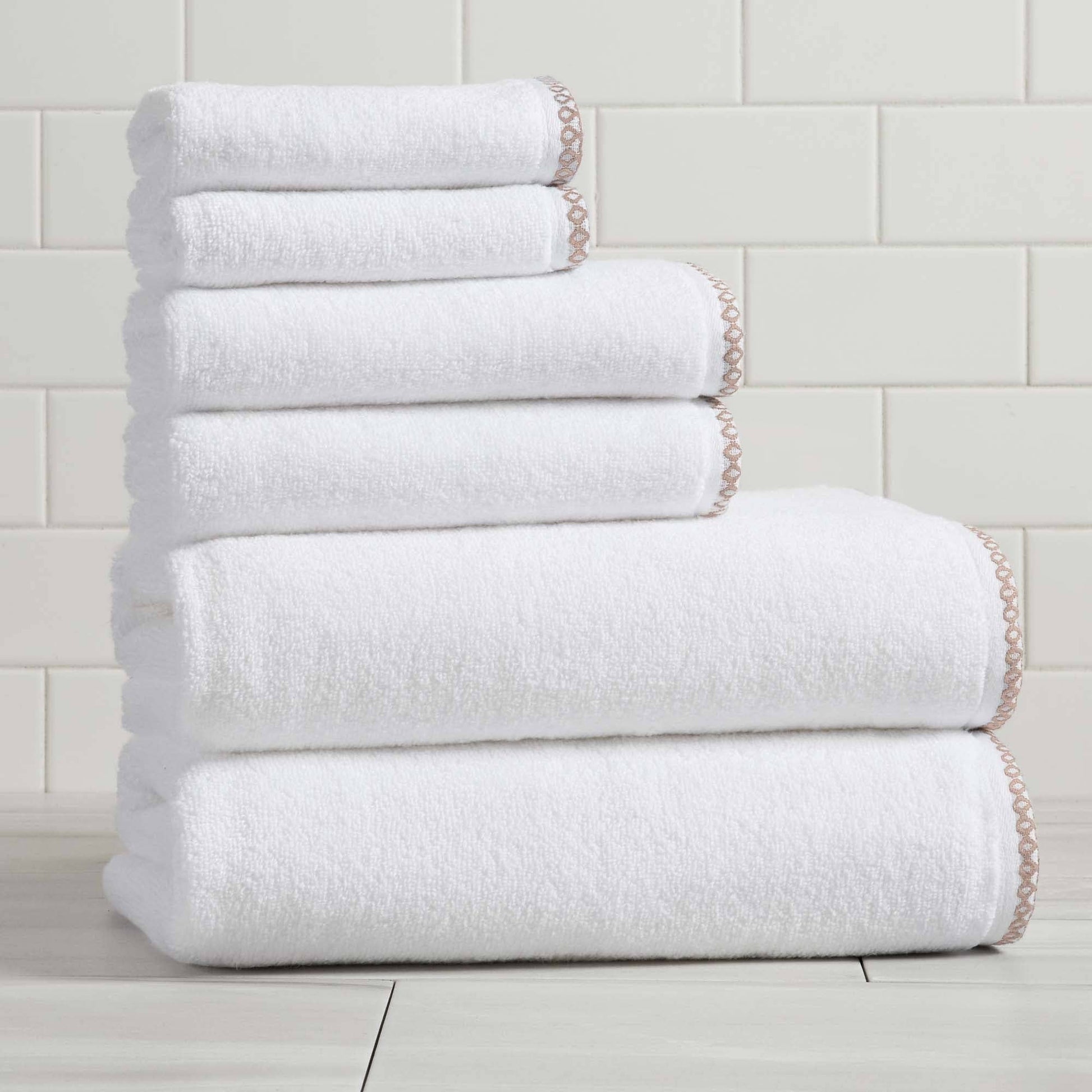 Stack of white towels on a light wooden floor with a tiled wall background