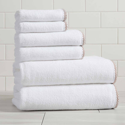 Stack of white towels on a light wooden floor with a tiled wall background