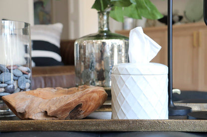 Decorative items on a shelf including a wooden bowl, glass container with pebbles, and a white geometric sculpture.