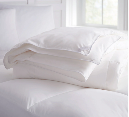 White comforter and pillow on a bed with a bright background