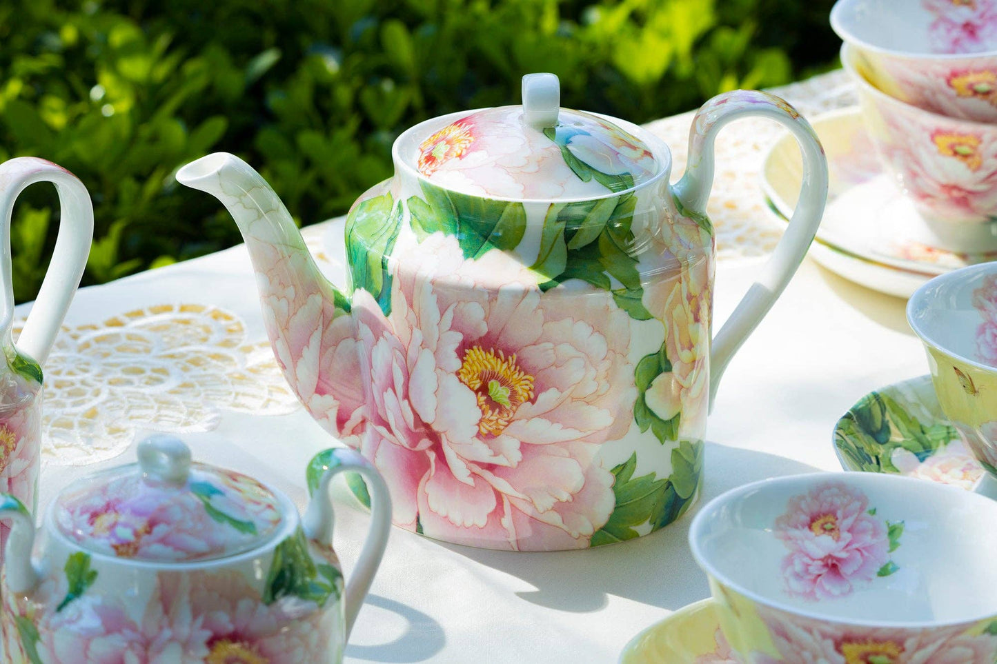 Floral teapot and cups on a table outdoors
