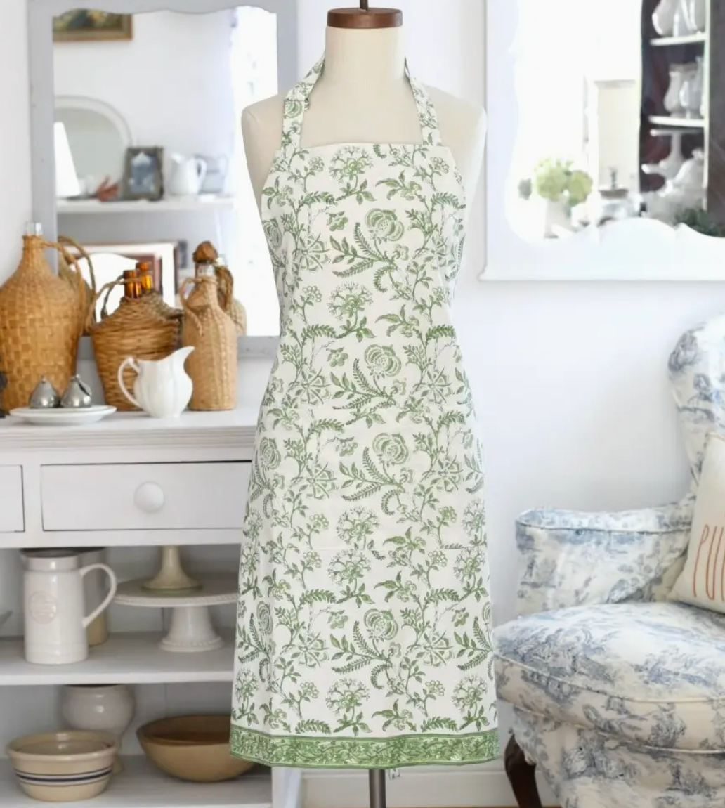 Floral apron on a mannequin in a home setting with shelves and decor.