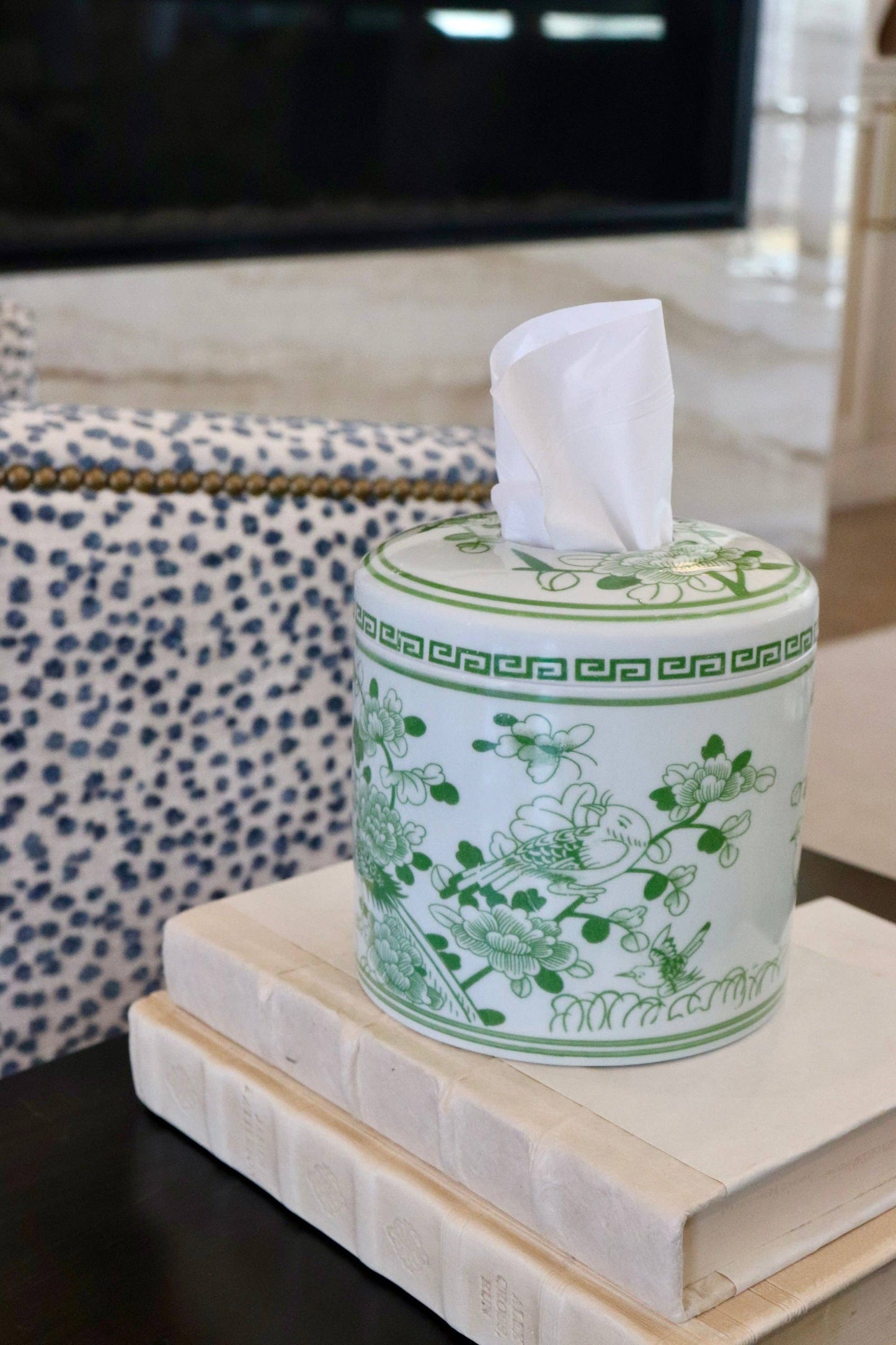Green ceramic tissue box with floral design on a stack of books