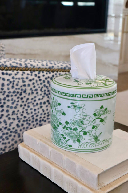 Green ceramic tissue box with floral design on a stack of books