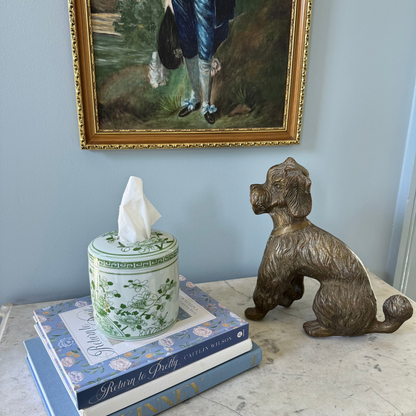 Decorative items including a tissue box, books, and a bronze dog statue on a surface with a painting in the background.