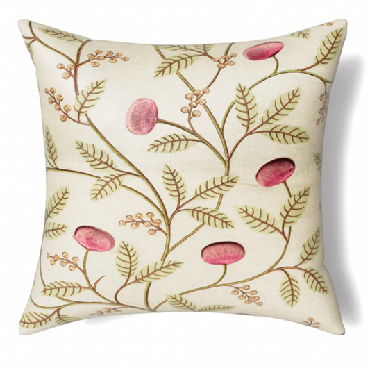 A square-shaped throw pillow with a beige background featuring a botanical design with green leaves and pink button-like pods.