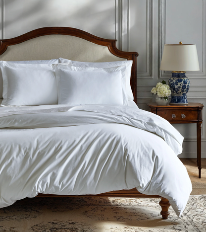 White bedding set on a bed with a wooden headboard in a bedroom setting.