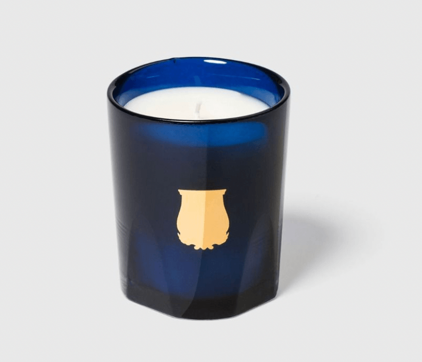 Trudon Madurai Candle in a blue glass holder with a white candle inside, displayed on a light gray background.