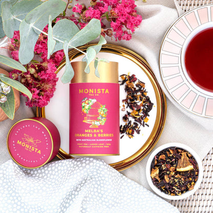 Monista tea packaging with flowers and tea leaves on a white surface