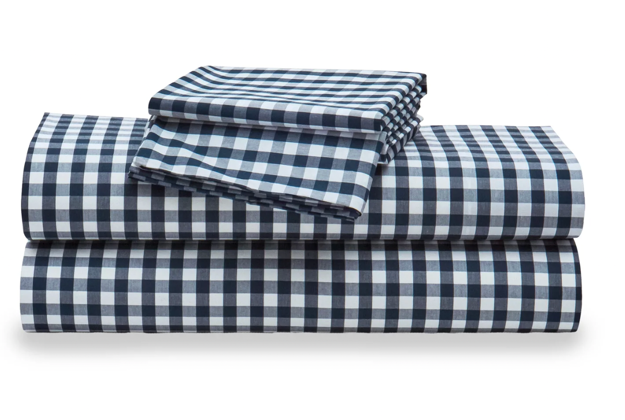 Folded blue and white checkered bed sheets on a white background
