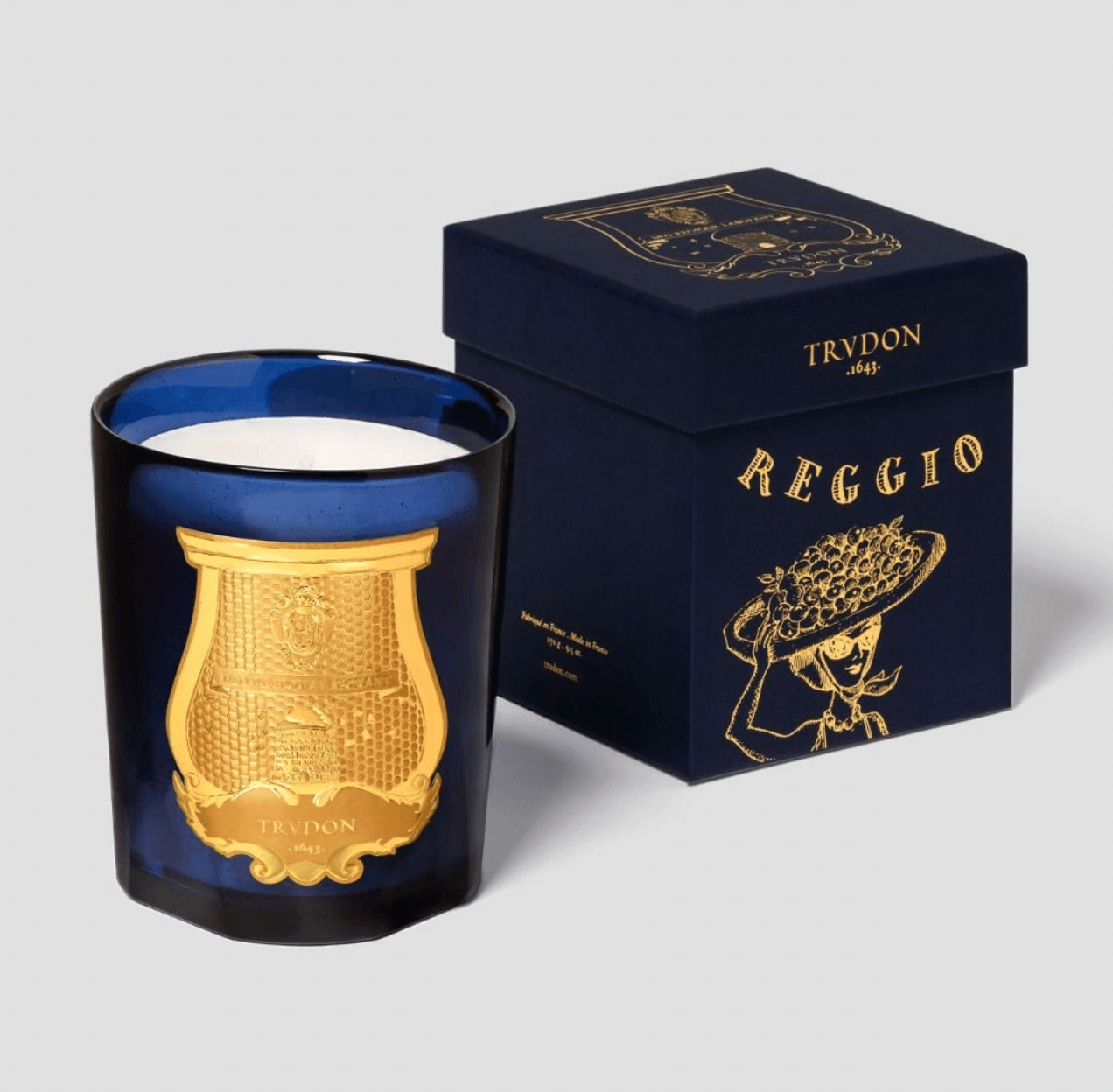 Trudon Reggio Candle shown with its dark travel case and matching blue glass vessel on a white background.