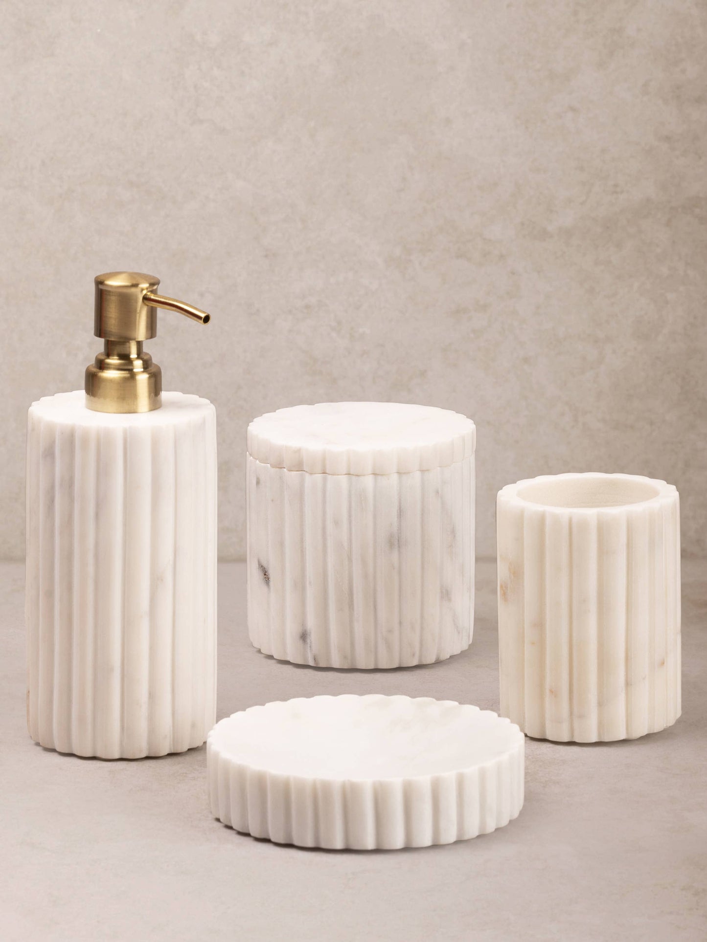 Set of marble-textured bathroom accessories including a soap dispenser, containers, and a lid on a neutral background.