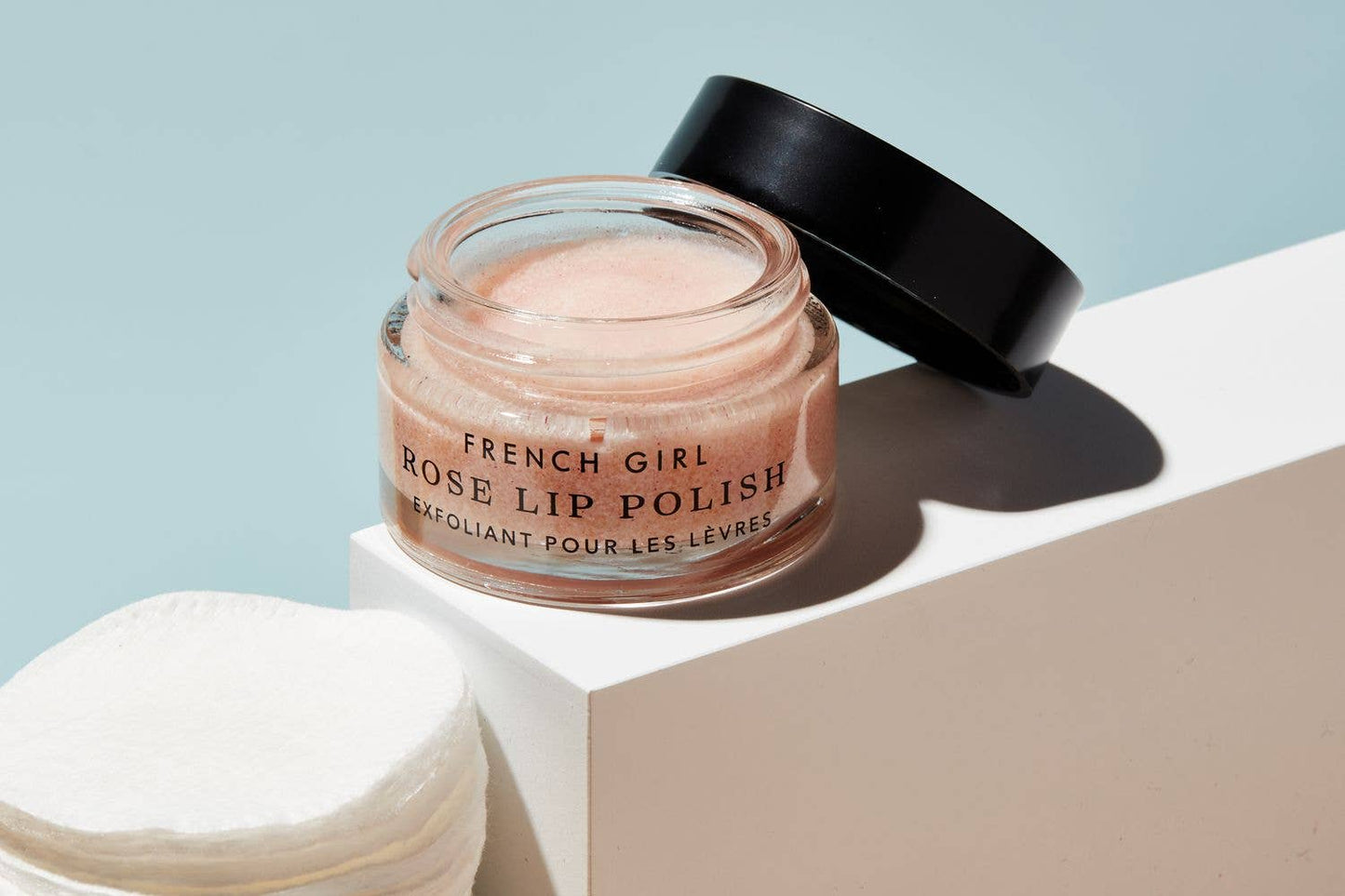 Jar of French Girl Rose Lip Polish on a white surface with a light blue background