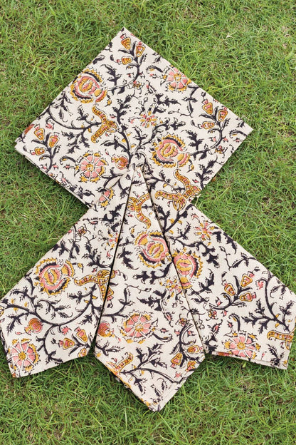 Light cream dinner napkin with ornate rose-and-paisley print, folded into star shape