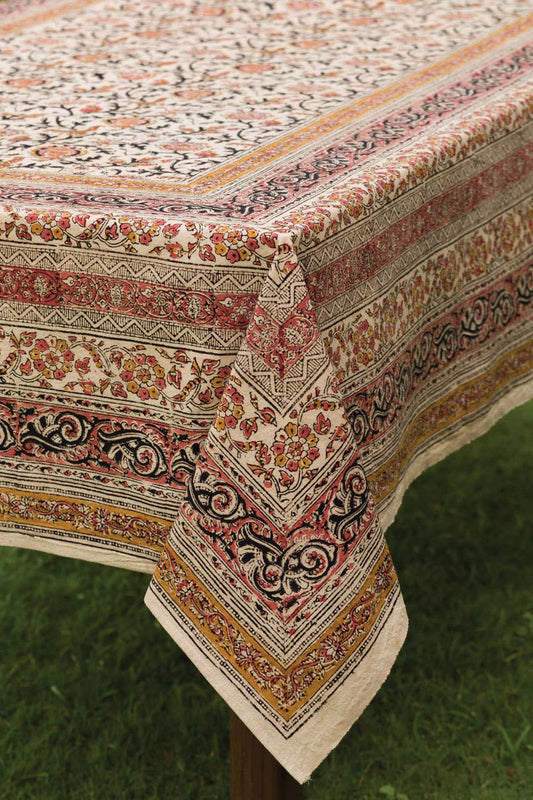 Cream patterned tablecloth with red and green floral border, corner detail