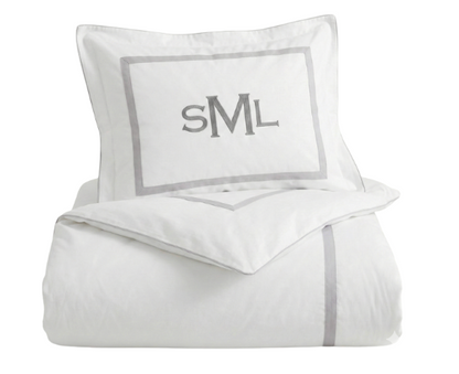 White bedding set with gray trim and monogram on a white background