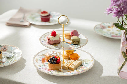 Three-tiered dessert stand with various pastries on a table with a vase of flowers.