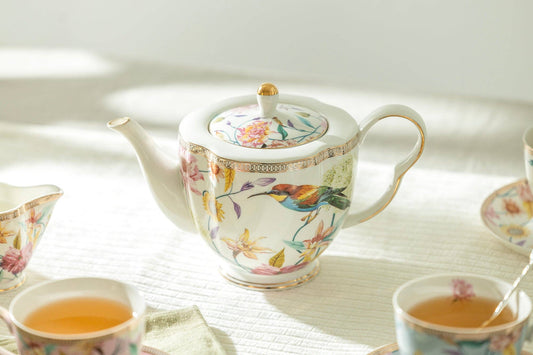 Decorative teapot and cups with floral patterns on a light surface