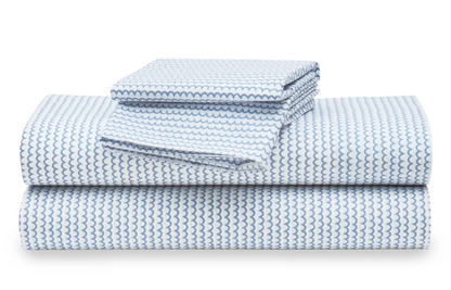 A stack of white percale sheet sets with blue stripes on the edges, neatly folded.
