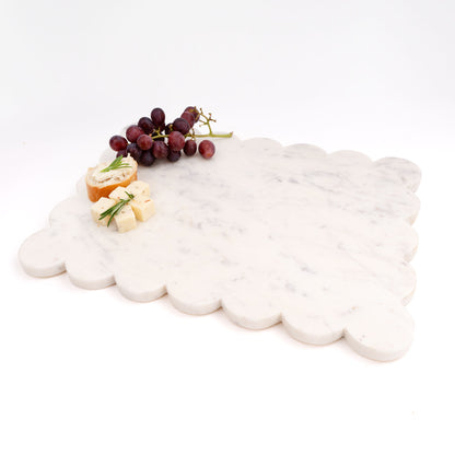 White marble cloud-shaped cutting board with fruits and cheese on a white background
