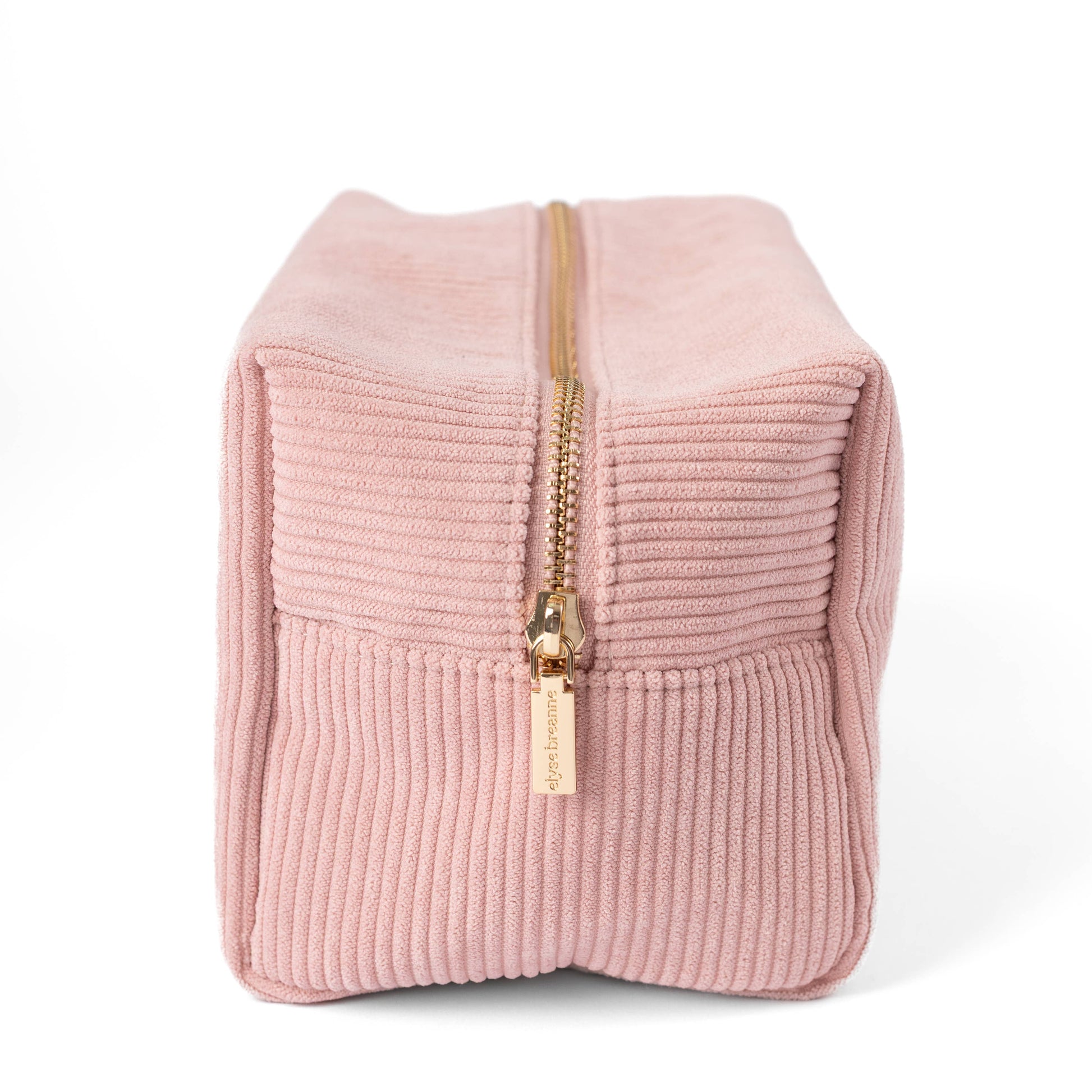 Pink corduroy cosmetic bag with front gold zipper pull and stitched panels