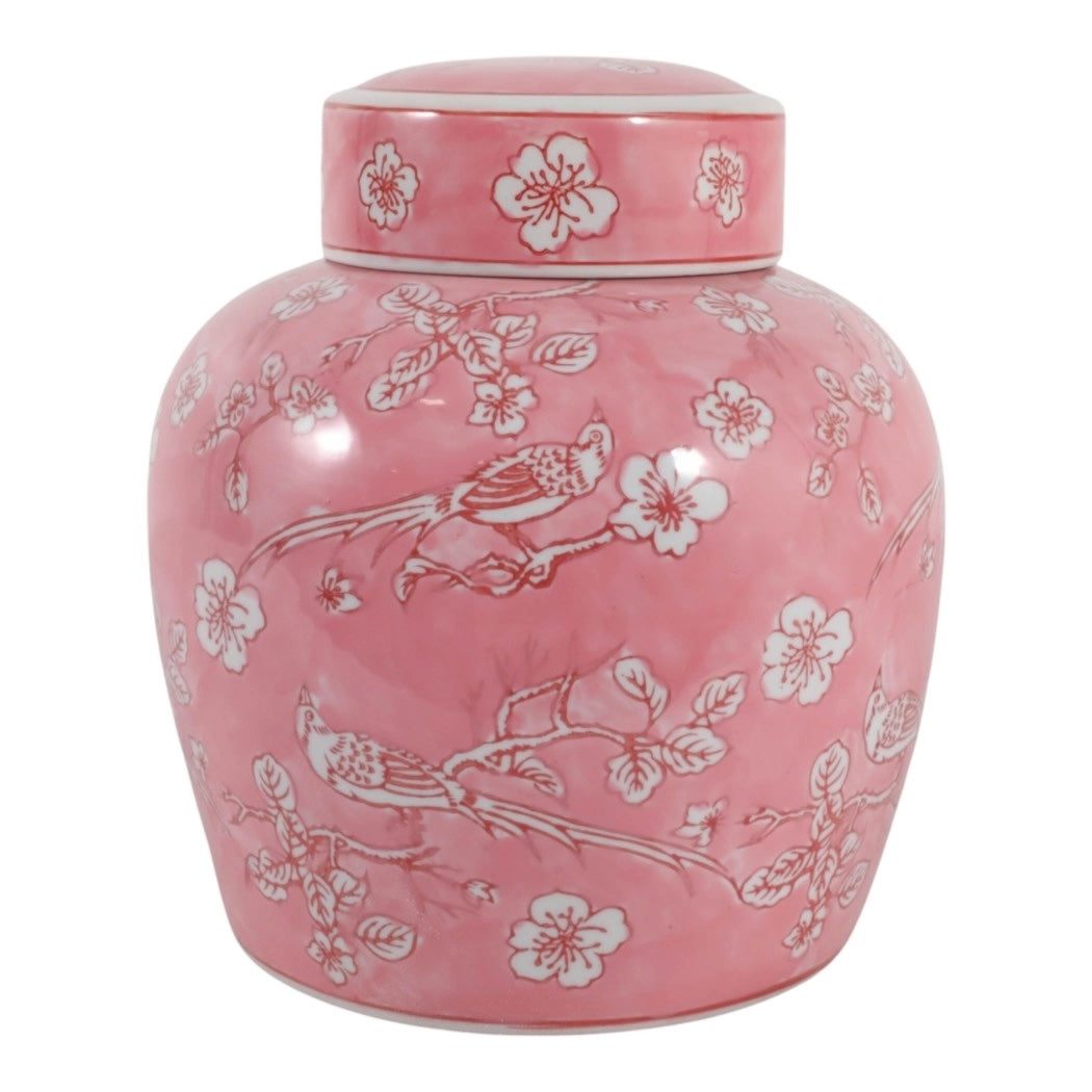 A pink ceramic tea jar with a matching lid, decorated with white floral blossoms and birds, shown against a plain white background.