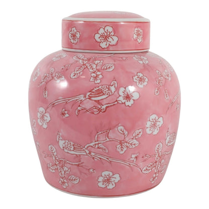 A pink ceramic tea jar with a matching lid, decorated with white floral blossoms and birds, shown against a plain white background.