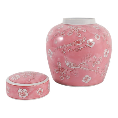 A pink ceramic jar with a matching lid, decorated with white floral and bird motifs, shown on a plain white background.